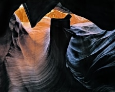 Looking up in Antelope Canyon near Paige, AZ.  Sunlight lit red rock and shadowed rock reflecting blue sky give a split red/blue effect.