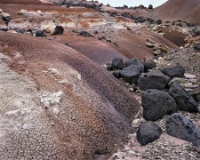 Black basalt boulders lie in a valley of bentonite in the Harnet Desert, Utah.  This colorful volcanic ash crushed into soft rock by time has purples, tans, browns, and other unexpected colors.
