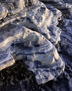 The sea has sculpted these blue striped rocks.  As the sun sets over the ocean, the warm glow on the rock contrasts with the dark blue stripes. Taken at Point Lobos, Monterey, CA.