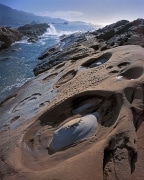 Waves crash and the tide goes out at Point Lobos Reserve near Carmel, CA.  The two toned rocks have odd potholes sculpted by these processes.